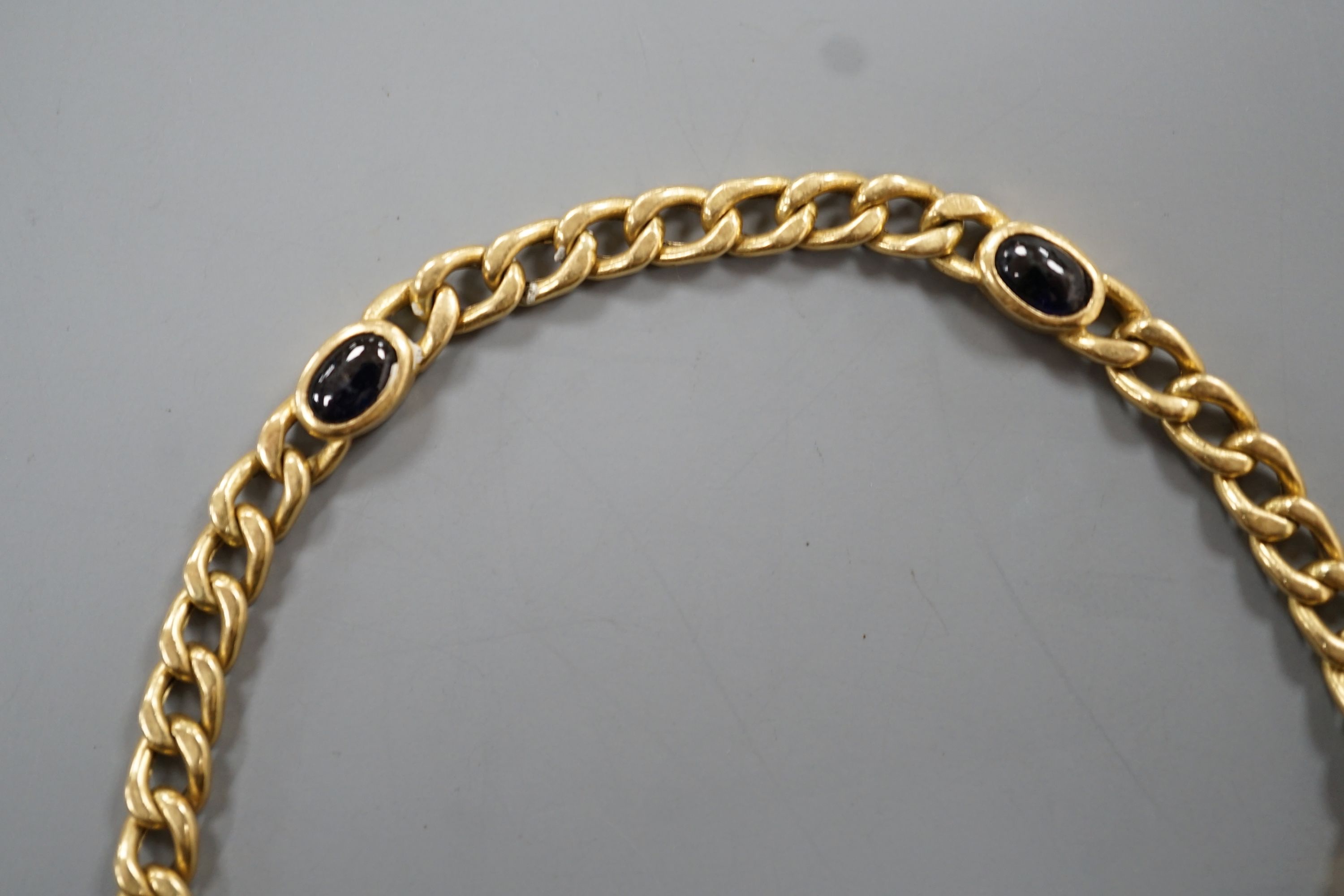 A yellow metal and blue cabochon stone set curb link bracelet, 18cm, gross weight 9 grams.